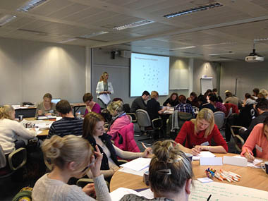 Photo of presenter and busy lecture room full of students