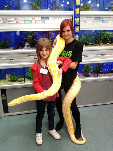 Two children holding a big albino python