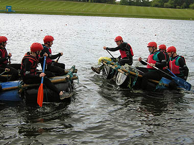 Two teams in makeshift rafts racing against each other