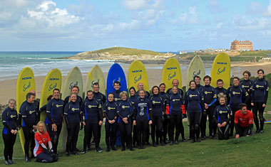 Surfers lined up in front of their surfboards