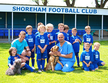 Shoreham Under 8s (left to right) Manager John Rhodie, Grove Lodge Vet Marc Abraham, and Shoreham under 8s with a couple of four-legged friends