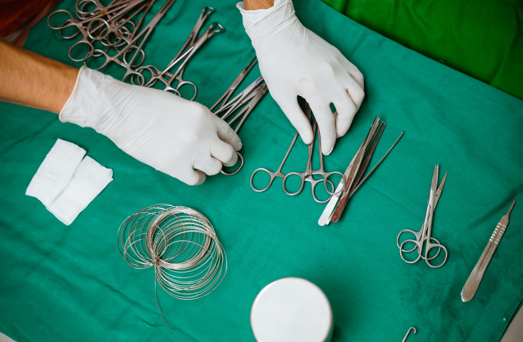 Overhead view of hands in sterile gloves and veterinary instruments