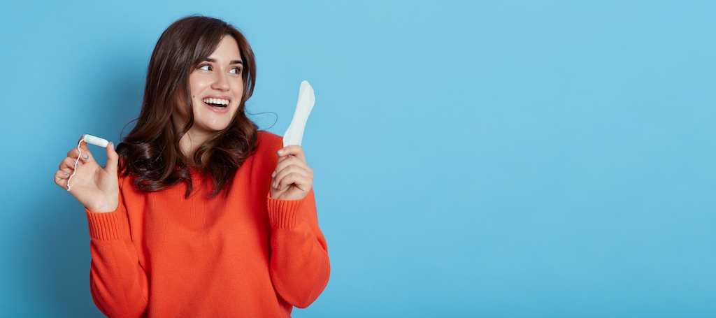 A woman holding a tampon and sanitary pad