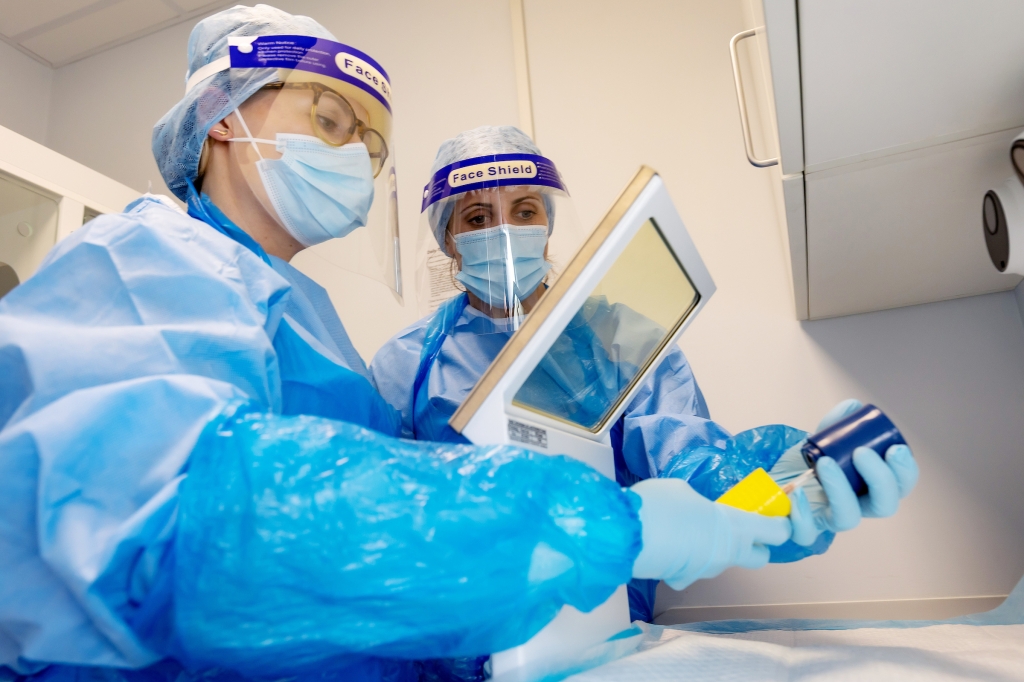 Two veterinary surgeons in protective gear examining a sample