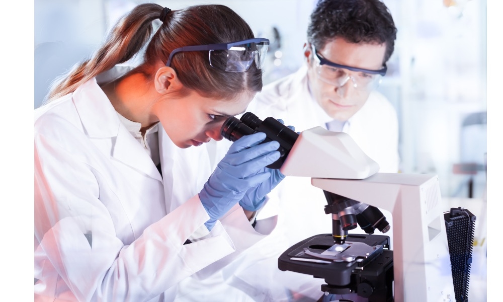 Two researchers looking through a microscope