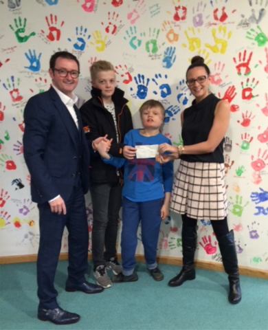 Mark Baxter, Archie Baxter (aged 13), and Harry Baxter (aged 15) present Ellie from T Hafan with the cheque.