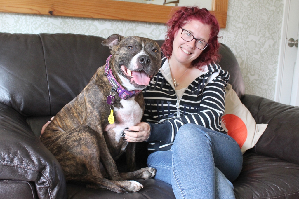 Happy dog owner sitting on sofa with dog