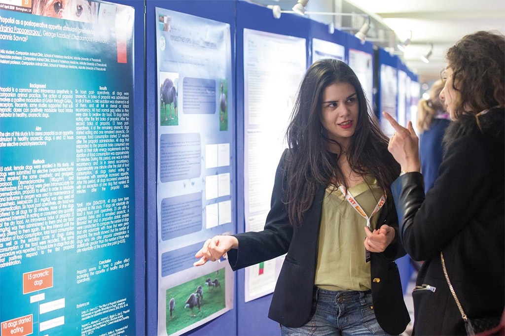 Two women standing talking in front of posters at a show